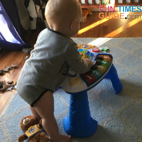 Little man standing with the Baby Einstein activity table.