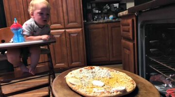 My toddler watching from his Keekaroo high chair as a I cook a pizza