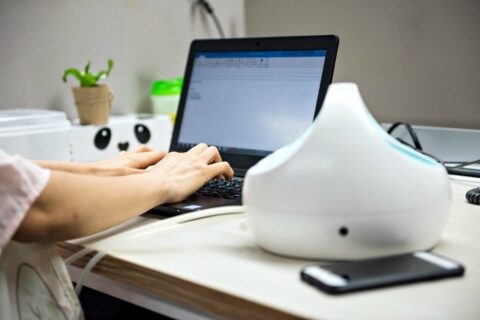 A busy mom pumps breast milk using an automatic breast pump machine while working on computer at work.