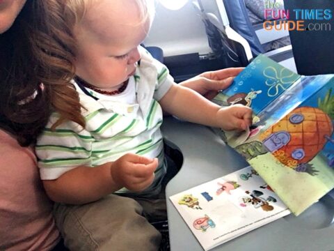 Passing time by putting stickers in a sticker book on the plane while sitting on my lap.