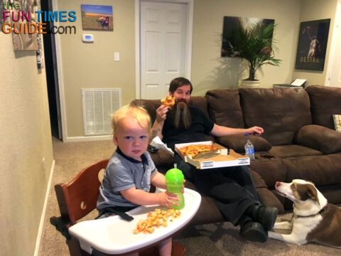 Dad and baby enjoying TV dinner night in the living room with a comfy couch and Keekaroo high chair.