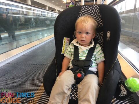 Riding in his car seat dolly on the escalator at the airport.